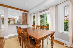 A dining area with a large wooden table, six chairs, and a brick fireplace. - Historic Annapolis Home  Walk to Downtown  3BR (Annapolis)