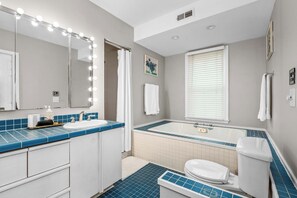 A bathroom with a vanity, sink, mirror with lights, bathtub, toilet, and a window with blinds. - Historic Annapolis Home  Walk to Downtown  3BR (Annapolis)