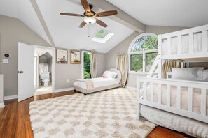 A bedroom with a bunk bed, a ceiling fan, a skylight, a large window, and a view of the outdoors. - Historic Annapolis Home  Walk to Downtown  3BR (Annapolis)