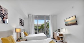 A hotel room with two beds, a desk, a chair, a TV, and a balcony with a view. - Hallandale Studio Pool, Gym & Shuttle (Hallandale Beach)