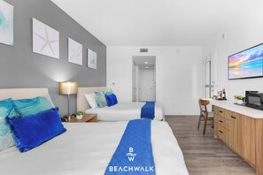 A hotel room with two beds, a desk, a TV, and a kitchenette. - Cozy Hallandale Studio Pool, Gym & Shuttle (Hallandale Beach)