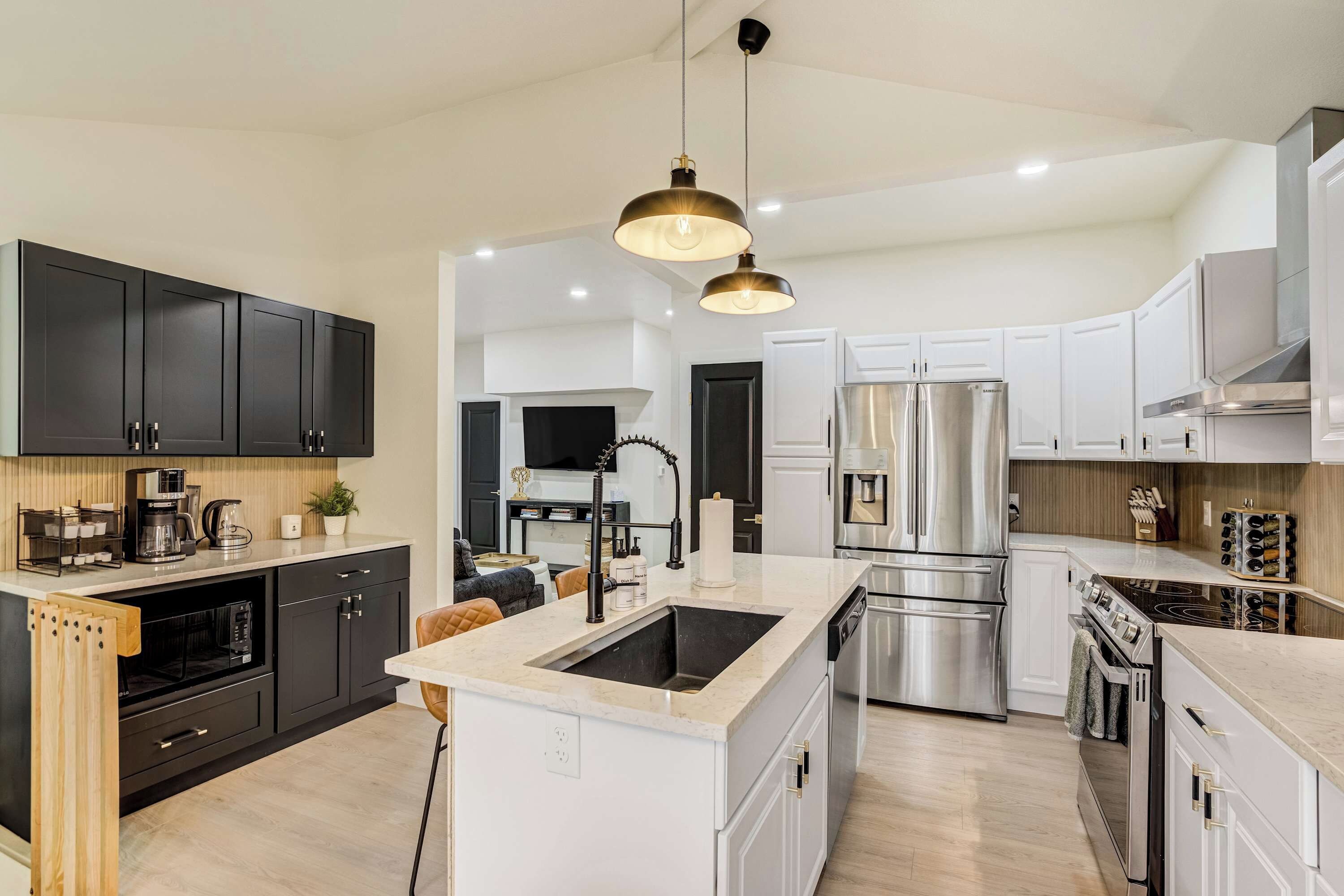 Una cocina moderna con una isla central, electrodomésticos de acero inoxidable y una lámpara colgante.