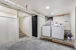 Una sala de lavandería con lavadora, secadora y calentador de agua.