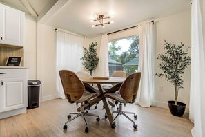 Una cocina moderna con una mesa de comedor, sillas, un bote de basura y una planta en maceta.
