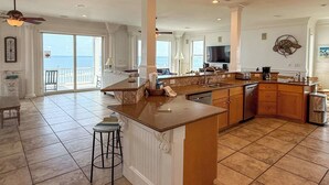 Uma cozinha espaçosa com uma ilha grande, uma sala de jantar com vista e uma sala de estar com televisão.