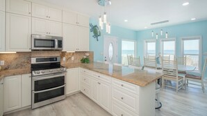 Een moderne keuken met witte kasten, roestvrijstalen apparatuur en een groot eiland.