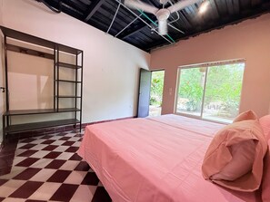 A room with a bed, a window, a ceiling fan, and a checkered floor.