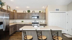 A modern kitchen with a central island, stainless steel appliances, and wooden cabinets. - WELCOME TO YOUR PIECE OF PARADISE (The Villages)