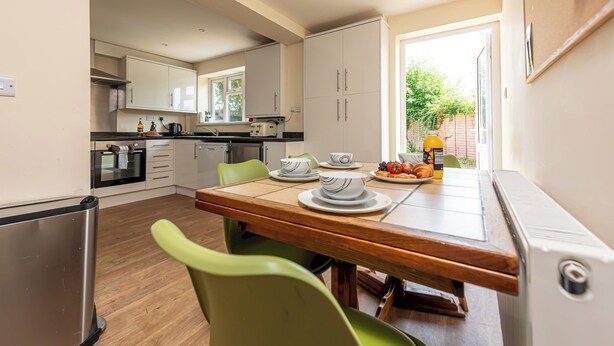 A modern kitchen with a dining table, chairs, and a view of the outdoors. - Budget-Friendly Group Stay in Newport - Pass the Keys (Newport)