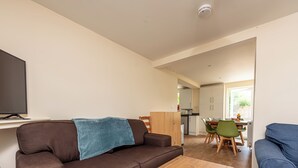 A living room with a brown sofa, a wooden coffee table, a blue sofa, a dining area with a table and chairs, and a kitchen in the background. - Budget-Friendly Group Stay in Newport - Pass the Keys (Newport)