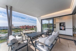 Ein moderner Balkon mit Esstisch, Sitzgelegenheiten und einem Kühlschrank.