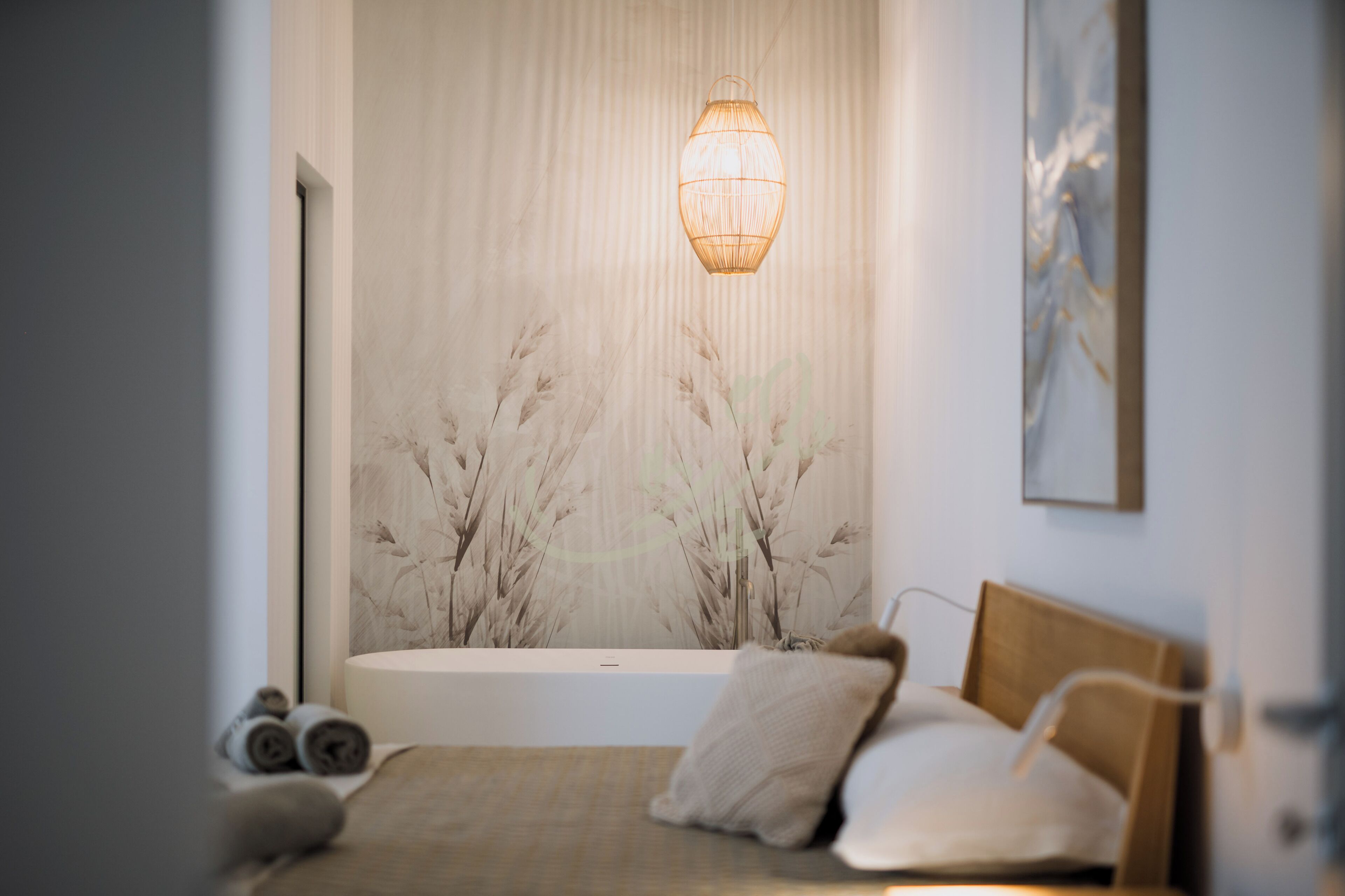 A bedroom with a bed, a wall-mounted lamp, and a large window with a view of trees.