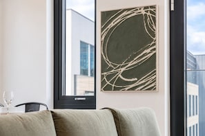 Ein modernes Zimmer mit einem großen Fenster, einer Couch und einem gerahmten abstrakten Kunstwerk.