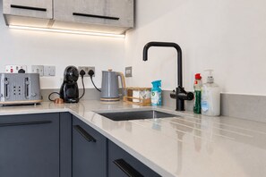 Eine moderne Küche mit integriertem Geschirrspüler, Kaffeemaschine, Wasserkocher und Spüle.