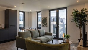 Sala moderna com sofá, mesa de jantar e uma ampla janela com vista para edifícios.