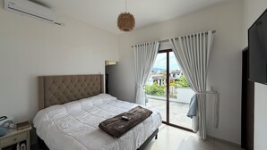 Un dormitorio con cama, mesita de noche, televisor y vistas al exterior.