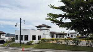 Un bâtiment moderne doté d’un toit plat, d’un patio couvert et d’une allée pavée avec des places de stationnement délimitées.