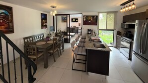 Une cuisine moderne dotée d’un îlot central, d’appareils électroménagers en acier inoxydable et d’un coin repas avec des meubles en bois.