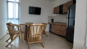 Una cocina moderna con armarios de madera, un refrigerador negro y un televisor de pantalla plana montado en la pared.