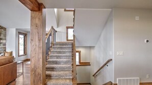 Eine Treppe mit Holelllauf und Teppichstufen, die zu einer oberen Etage führt.