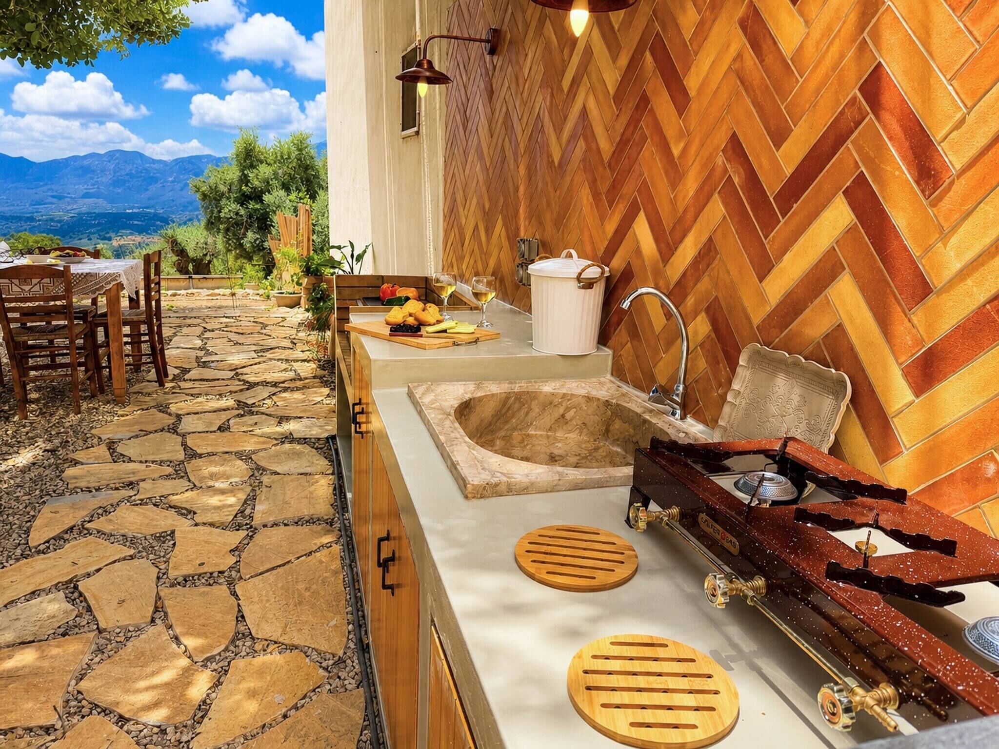 A kitchen with a stone-tiled floor, wooden herringbone backsplash, a sink, a stove, and a dining area with a table and chairs.