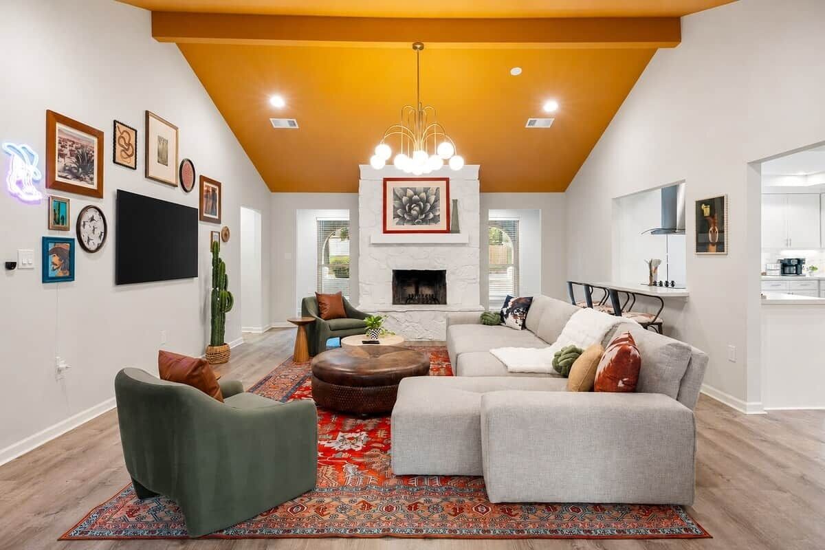 A living room with a fireplace, sofa, and coffee table, and a kitchen in the background.