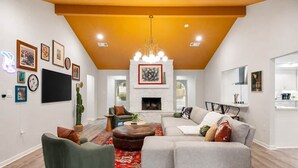 Un salón con chimenea, sofá y mesa de centro, y una cocina al fondo.