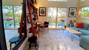 A spacious living room with a large window, a wooden bookshelf, a sofa, and a coffee table. - Panoramic views on Beacon Hill, Seattle (Seattle)
