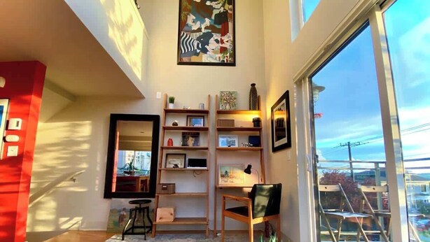 A modern living room with a large window, wooden shelves, a desk, and a chair. - Panoramic views on Beacon Hill, Seattle (Seattle)