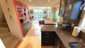 A modern kitchen with a central island, a dining area with a sofa, and a staircase leading to another level. - Panoramic views on Beacon Hill, Seattle (Seattle)