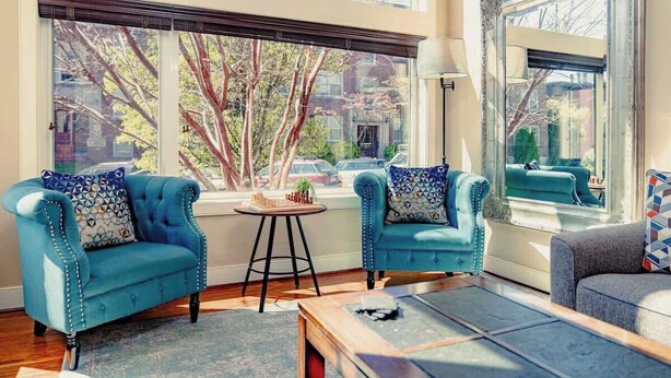 Une pièce avec deux fauteuils bleus, une petite table ronde et un canapé.