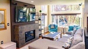 Un salon moderne avec une cheminée, un téléviseur à écran plat, un canapé et une table basse.