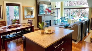 Un salon moderne doté d’une cheminée, d’un coin repas et d’une grande fenêtre donnant sur l’extérieur.