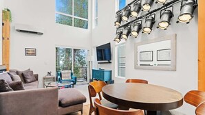 A modern living room with a sofa, chairs, a dining table, and a large window. - Capitol Hill private terrace & mountain views (Seattle)