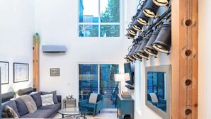 A modern living room with a sofa, coffee table, and chairs, large windows, and a unique ceiling light fixture. - Capitol Hill private terrace & mountain views (Seattle)