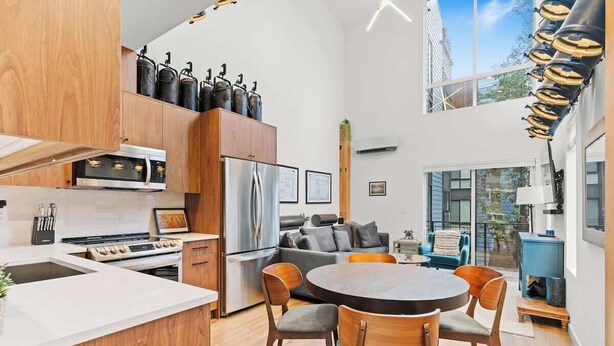 A modern kitchen with a central island, a dining area with a round table and chairs, and a living space with a sofa and a coffee table. - Capitol Hill private terrace & mountain views (Seattle)