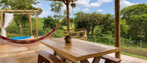 A wooden table with benches, a hammock, and a swing under a wooden pergola.