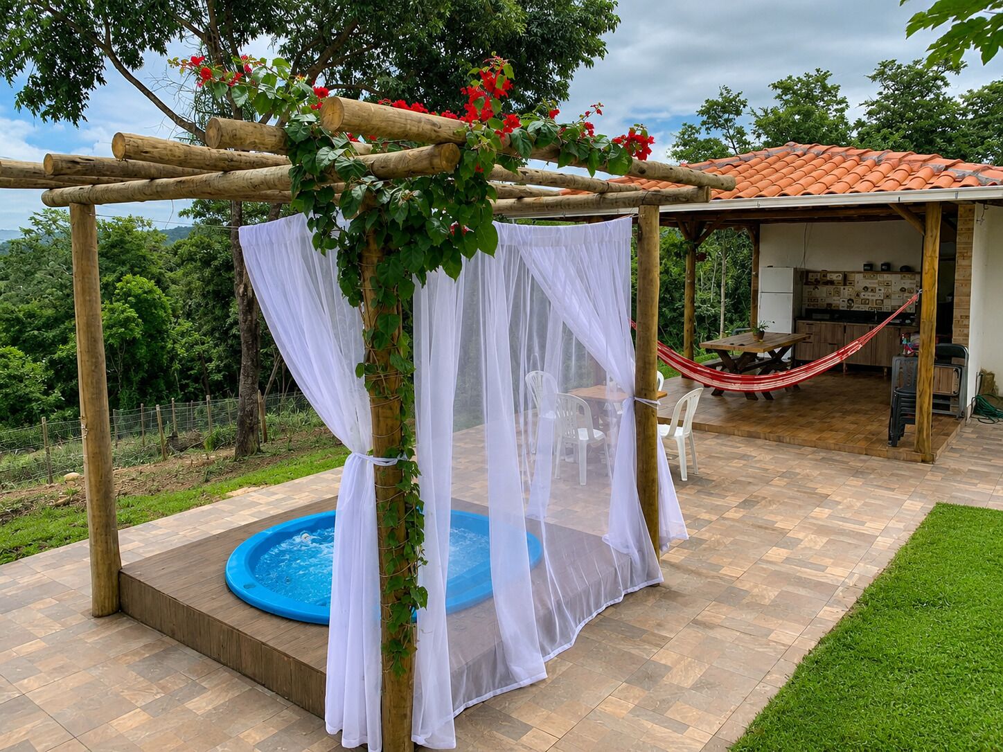 A gazebo with a pool, outdoor seating, and a kitchen area.