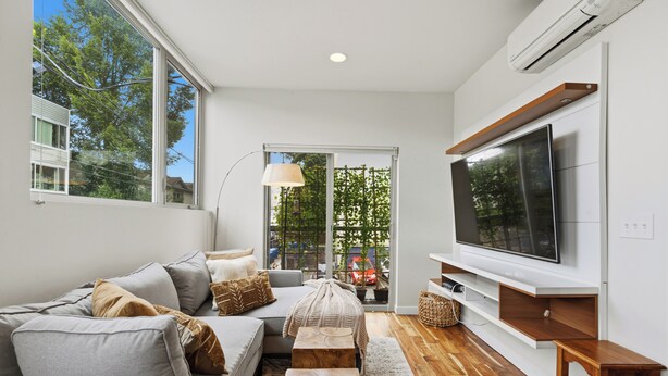 A modern living room with a large TV, a sofa, and a wooden coffee table. - Spacious Townhome in an Unbeatable Location (Seattle)
