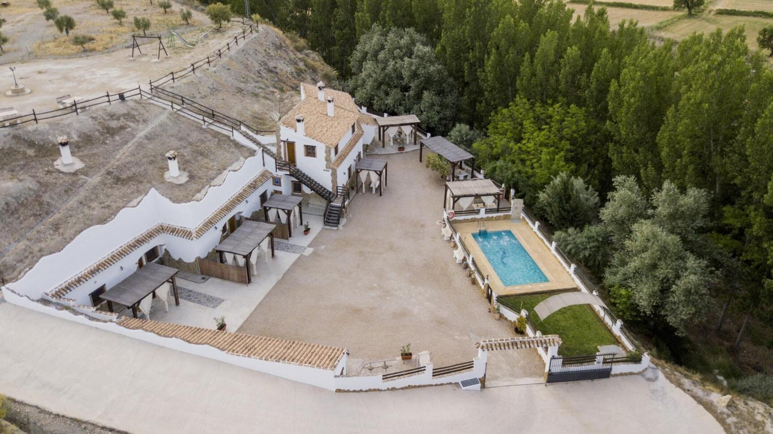 Une grande maison avec une piscine, un espace extérieur aménagé et un jardin.
