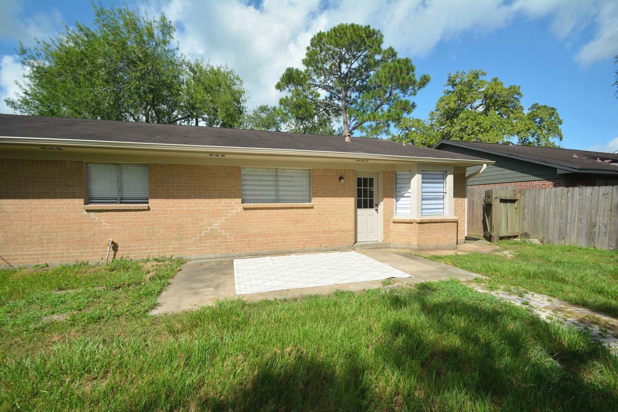A single-story brick house with a front door, two windows, and a small front yard.