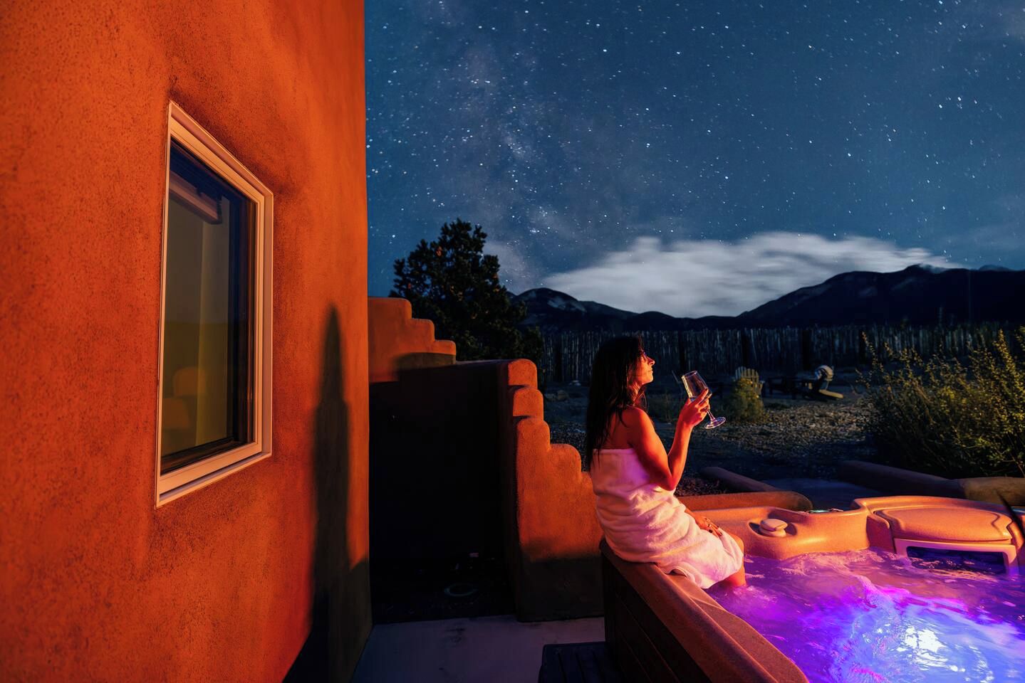 A person relaxing by a hot tub with a starry night sky in the background.
