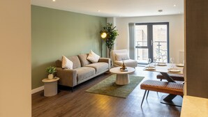 A modern living room with a sofa, armchair, coffee table, and a dining area with chairs and a table. - Modern York Apartment - Free Parking - Sleeps 7 (York)