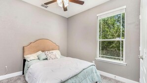 Une chambre à coucher avec un lit, une fenêtre et un ventilateur de plafond.