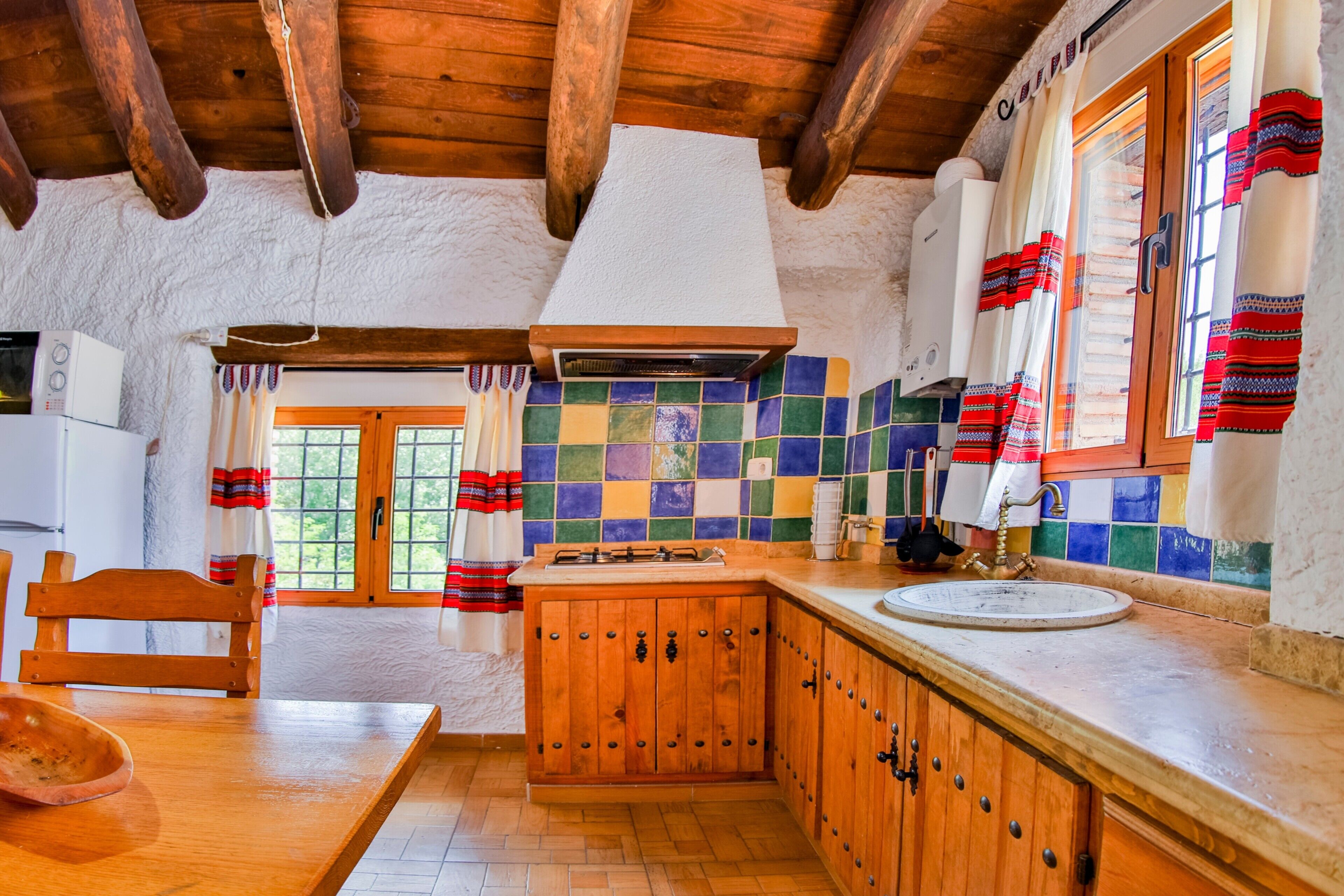 Una cocina rústica con armarios de madera, salpicadero de azulejos y techo de madera.