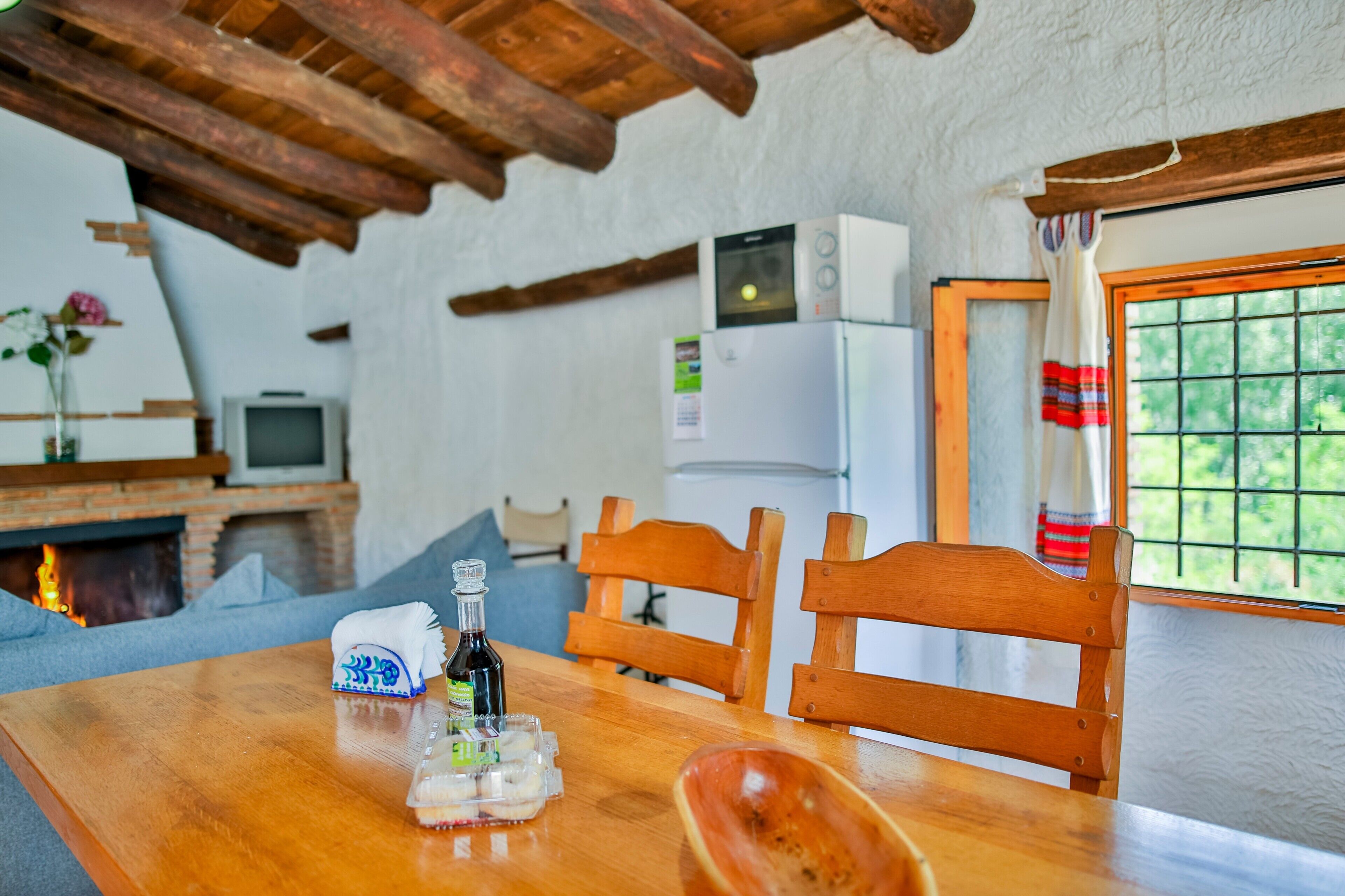 Een houten eettafel met stoelen, een fles en bakken met eten.