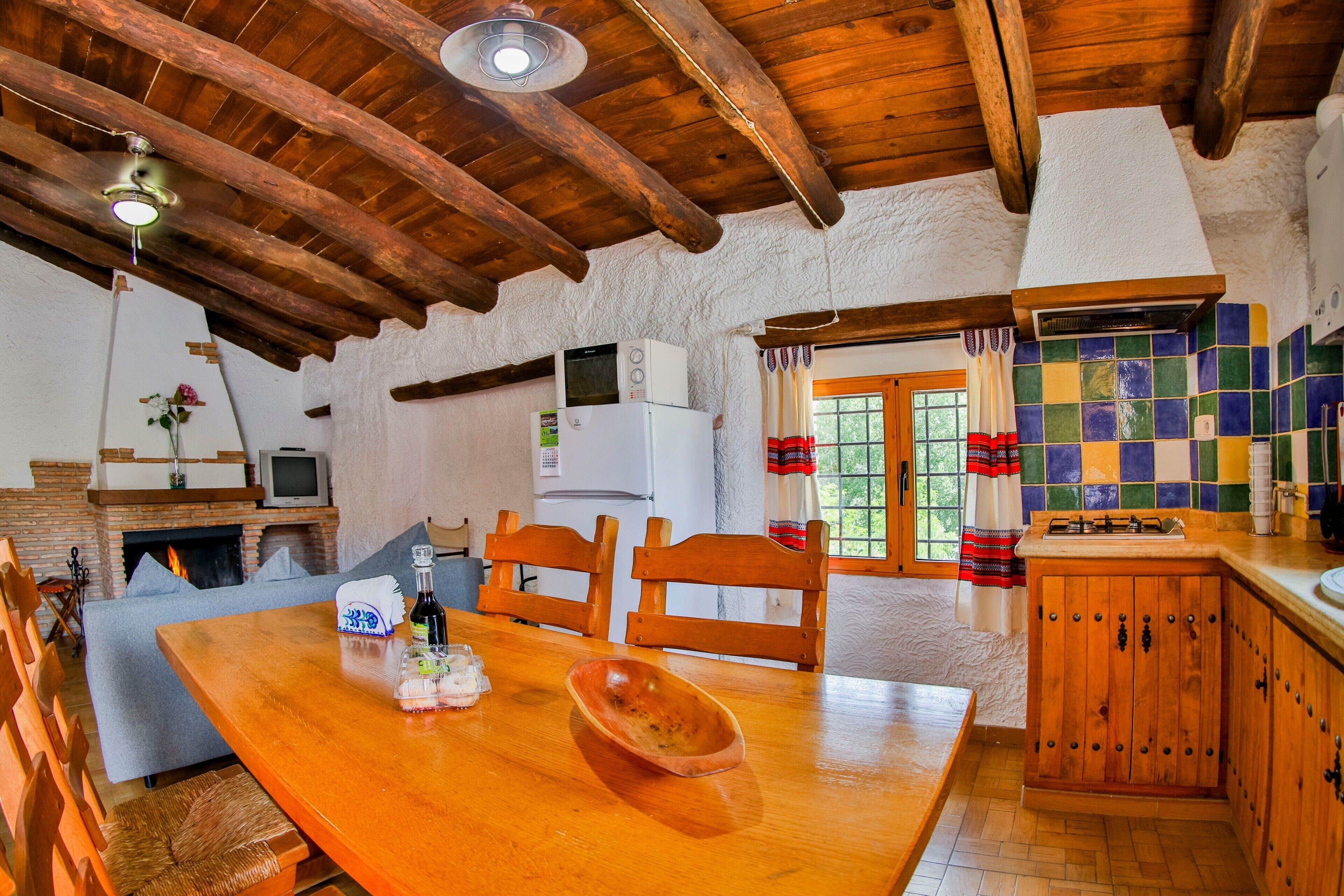 Une cuisine rustique avec une table en bois, des chaises, un four à micro-ondes et une cheminée.