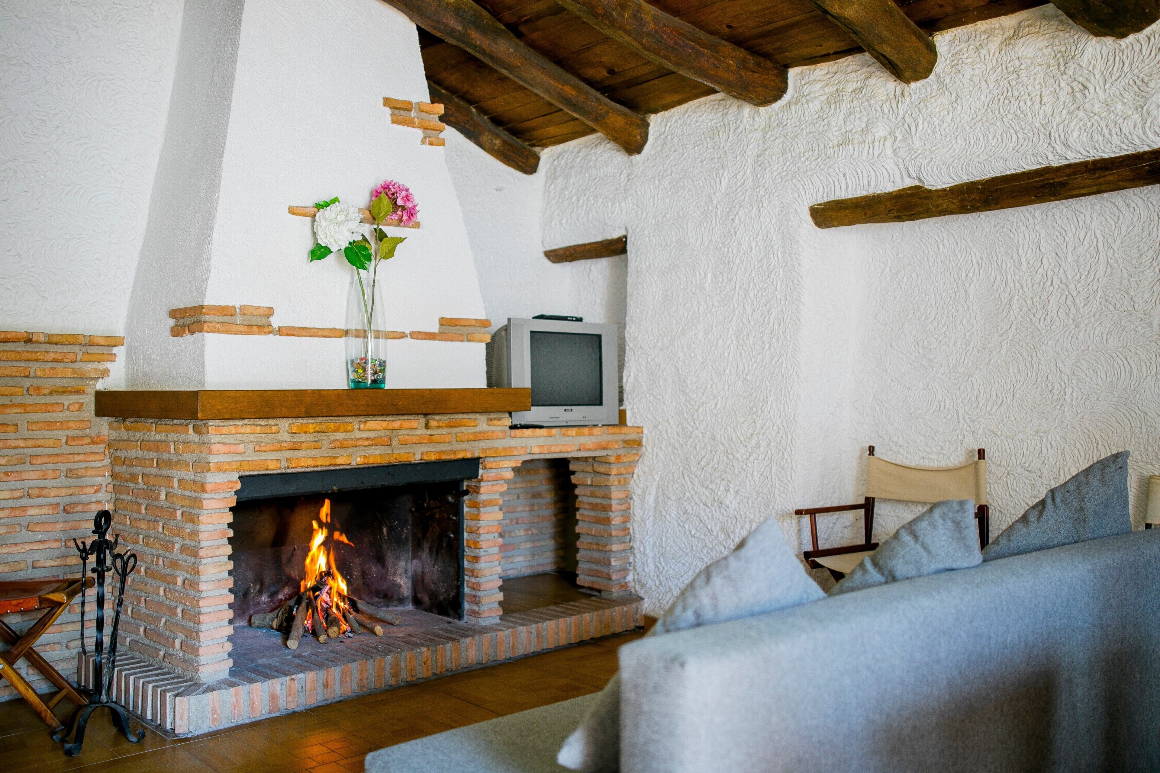 Una sala de estar con chimenea de ladrillo, un televisor encima y un sofá.