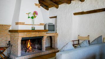 Una sala de estar con chimenea de ladrillo, un televisor encima y un sofá.