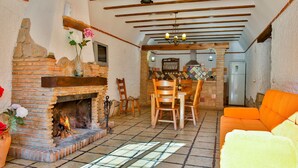 A cozy living room with a fireplace, wooden furniture, and a tiled floor.